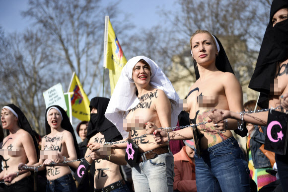 8일(현지시간) 프랑스 파리에서 ‘세계 여성의 날’을 맞아 퍼레이드가 열린 가운데 국제여성인권단체 페멘(FEMEN)의 리더 인나 셰브첸코(오른쪽)와 회원들이 상의를 탈의한 채 체인에 손을 묶고 행진에 참여하고 있다. ⓒAFPBBNews=News1