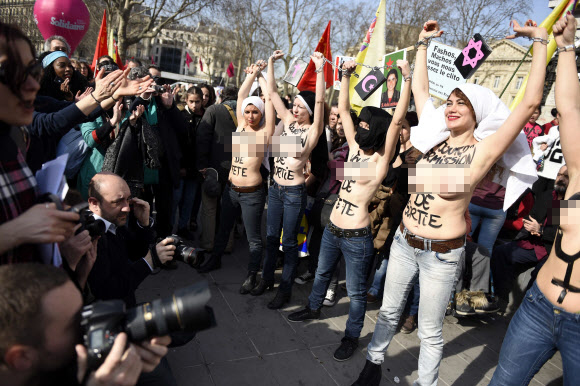 8일(현지시간) 프랑스 파리에서 ‘세계 여성의 날’을 맞아 퍼레이드가 열린 가운데 국제여성인권단체 페멘(FEMEN)의 회원들이 상의를 탈의한 채 체인에 손을 묶고 행진에 참여하고 있다. ⓒAFPBBNews=News1