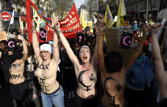 8일(현지시간) 프랑스 파리에서 ‘세계 여성의 날’을 맞아 퍼레이드가 열린 가운데 국제여성인권단체 페멘(FEMEN)의 회원들이 상의를 탈의한 채 체인에 손을 묶고 행진에 참여하고 있다. ⓒAFPBBNews=News1