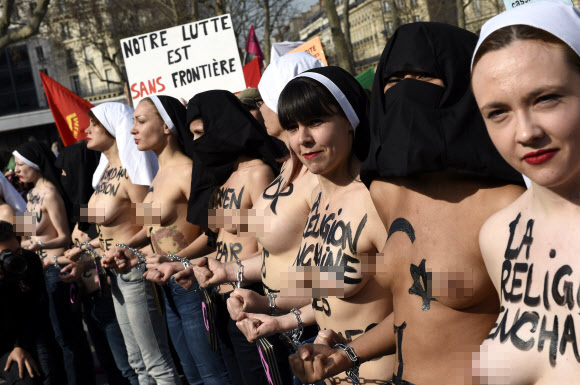 8일(현지시간) 프랑스 파리에서 ‘세계 여성의 날’을 맞아 퍼레이드가 열린 가운데 국제여성인권단체 페멘(FEMEN)의 회원들이 상의를 탈의한 채 체인에 손을 묶고 행진에 참여하고 있다. ⓒAFPBBNews=News1