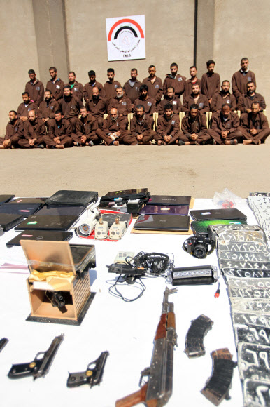 16일(현지시간) 이라크 수도 바그다드에 위치한 이라크 국가정보원 청사 앞에 이라크 정부군이 이슬람 수니파 무장단체 ‘이슬람국가’(IS) 대원으로 추정되는 31명의 인질을 포위하고 있다. 사진은 IS 대원 31명과 그들이 사용한 무기를 압수한 모습.  ⓒAFPBBNews=News1