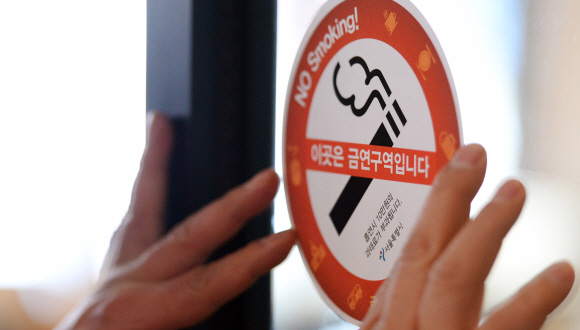 석달간의 계도 기간이 끝나고 실내금연구역 흡연시 과태료 부과가 실시되는 1일 서울 중구 한 커피숍에서 중구 보건소 직원들이 현장 단속을 하면서 금연 스티커를 붙이고 있다.  박윤슬 기자 seul@seoul.co.kr