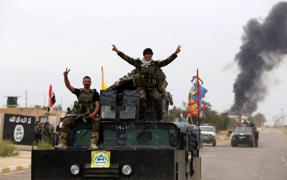 4월 1일(현지시간) 이라크 살라딘 주의 주도 티크리트에서 시아파 민병대원들이 치열한 교전 끝에 이슬람 국가(IS) 무장 세력을 격퇴한 후 탱크에 올라서서 양 손으로 V를 그리고 있다. ⓒAFPBBNews=News1