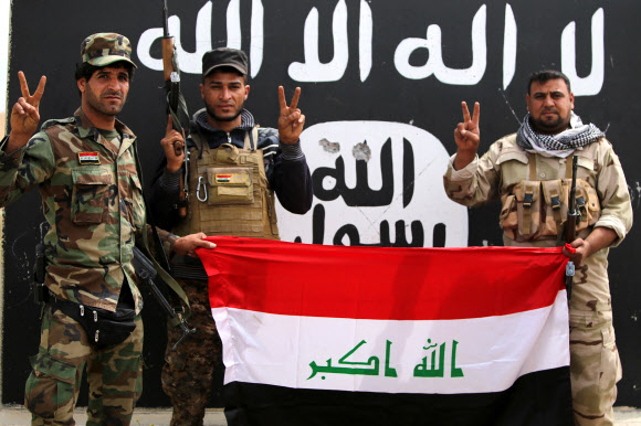 1일(현지시간) 이라크 살라딘 주의 주도 티크리트에서 시아파 민병대원들이 교정 중 빼앗은 이슬람 국가 깃발을 들고 포즈를 취하고 있다.  ⓒAFPBBNews=News1