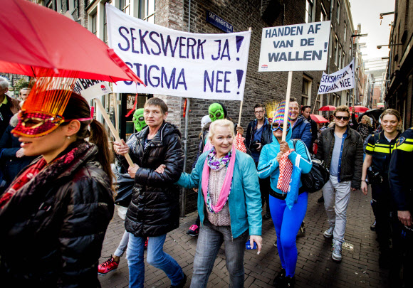 9일(현지시간) 마스크로 얼굴을 가린 수백 명의 성매매업소 종사자들과 이들을 지지하는 사람들이 암스테르담 시내 홍등가에서 호객용 유리 진열시설 철거에 반대하는 시위를 하고 있다. AFP=연합