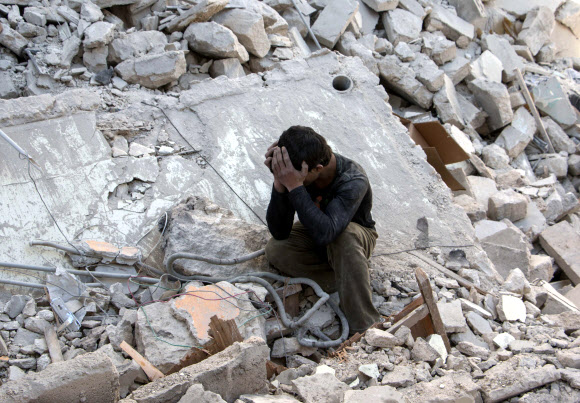 공습으로 파괴된 건물 잔해에 앉아 울고 있는 시리아 소년