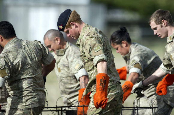 Britain’s Prince Harry (C) helps carry a “hungi”, a Maori food basket, to a waiting truck with New Zealand Army personnel during a visit to Linton Military Camp in Linton, near Palmerston North, on May 13, 2015.