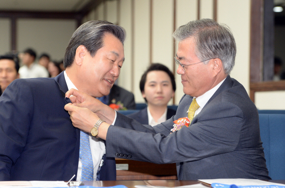 28일 서울 여의도 국회도서관에서 열린 국회 광주유니버시아드대회 지원단 발대식에 참석한 새정치민주연합 문재인 대표가 새누리당 김무성 대표에게 대회뱃지를 달아주고 있다 . 2015. 5. 28 정연호 tpgod@seoul.co.kr