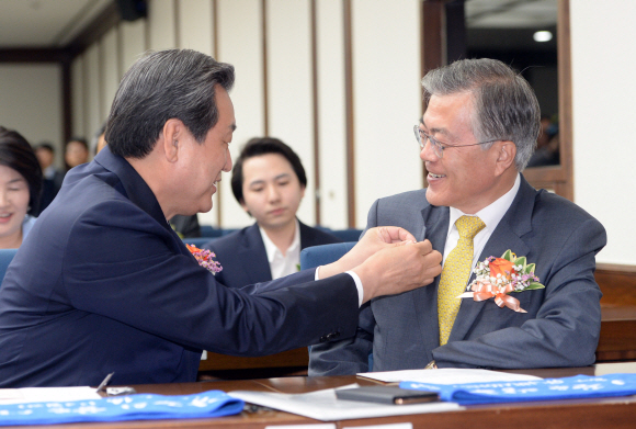 28일 서울 여의도 국회도서관에서 열린 국회 광주유니버시아드대회 지원단 발대식에 참석한 새누리당 김무성 대표가 새정치민주연합 문재인 대표에게 대회뱃지를 달아주고 있다 . 2015. 5. 28 정연호 tpgod@seoul.co.kr