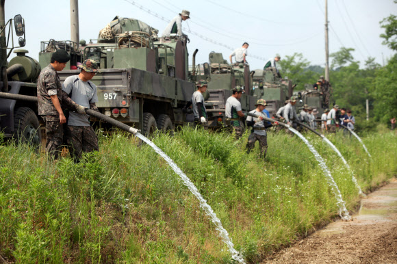 군장비 이용해 통일촌 논에 물대기하는 장병들