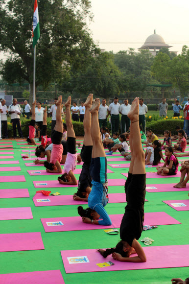 19일 인도 뉴델리 도심 라지파트에서 여학생들이 고난도의 요가 동작을 선보이고 있다.  이날 학생, 공무원과 시민들은 오는 21일 세계 요가의 날에 선보일 단체 요가 수련 시범 예행연습을 했다. 2015.6.19/ 연합뉴스
