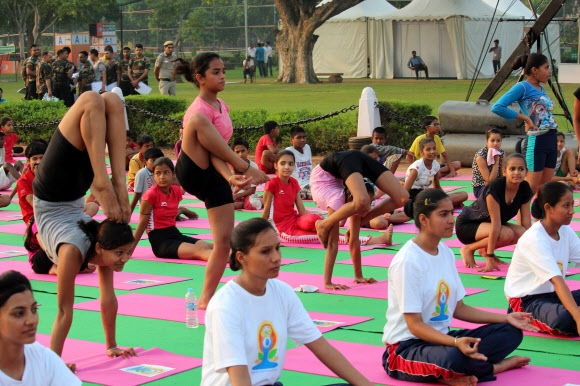 19일 인도 뉴델리 도심 라지파트에서 여학생들이 고난도의 요가 동작을 선보이고 있다.  이날 학생, 공무원과 시민들은 오는 21일 세계 요가의 날에 선보일 단체 요가 수련 시범 예행연습을 했다. 2015.6.19/ 연합뉴스