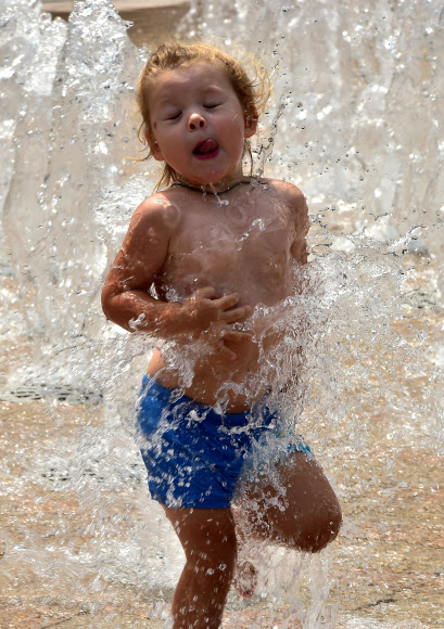 여자 아이가 23일(현지시간) 전국적으로 기온이 32도를 기록하는 가운데 서울 도심 분수의 물을 맞으며 더위를 식히고 있다. 대한민국은 거의 두달 가량 가뭄이 계속되고 있다.  ⓒ AFPBBNews=News1