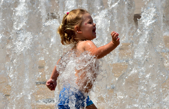 여자 아이가 23일(현지시간) 전국적으로 기온이 32도를 기록하는 가운데 서울 도심 분수의 물을 맞으며 더위를 식히고 있다. 대한민국은 거의 두달 가량 가뭄이 계속되고 있다.  ⓒ AFPBBNews=News1