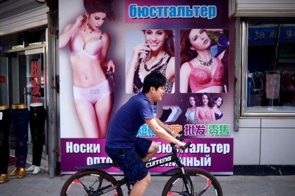 중국 헤이룽장성에 있는 국경도시인 헤이허시에서 4일(현지시간) 자전거를 탄 한 남성이 키릴문자가 써진 광고판 옆을 지나가고 있다. ⓒ AFPBBNews=News1