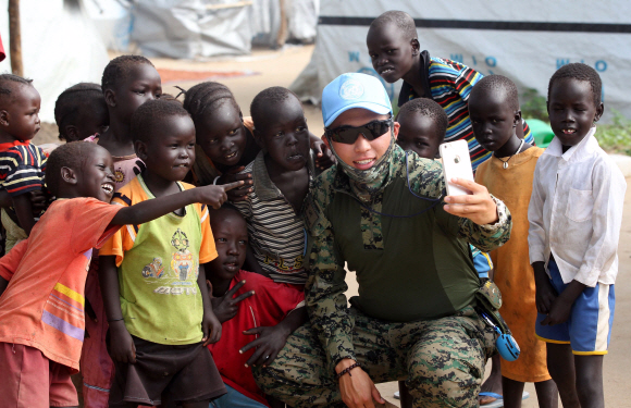9일 (현지시간) 남수단 보르시의 전쟁 난민 2300여명이 모여있는 POC(Protection of Civilion)에서 한 한빛부대 대원이 어린이들과 셀카를 찍고있다.  2015. 07. 09 사진공동취재단