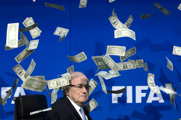 20일(현지시간) 스위스 취리히에서 열린 기자회견 도중 한 영국 코미디언이 던진 가짜 돈다발이 제프 블래터 국제축구연맹(FIFA) 회장 주위로 뿌려지고 있다.  국제축구연맹(FIFA)은 내년 2월26일 차기 회장선거를 연다고 밝혔다. ⓒ AFPBBNews=News1
