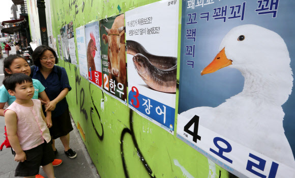 절기상 중복인 23일 오후 서울 종로를 찾은 한 가족이 의료정보 애플리케이션 ‘굿닥’의 ‘제1대 보양식통령 선거’ 포스터를 살펴보고 있다. 오는 26일까지 진행하는 보양식통령 선거는 굿닥 어플내 굿닥캐스트에서 투표하면 된다.  연합뉴스