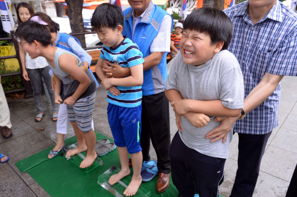 13일 서울시 서초구 뒷벌어린이공원에서 방배골 여름 축제 ’어린이 얼음 위 오래 서있기’ 대회가 열리자 참가 어린이들이 얼음 위에 올라서서 찬발의 시려움을 참아내고 있다.  이언탁 기자 utl@seoul.co.kr