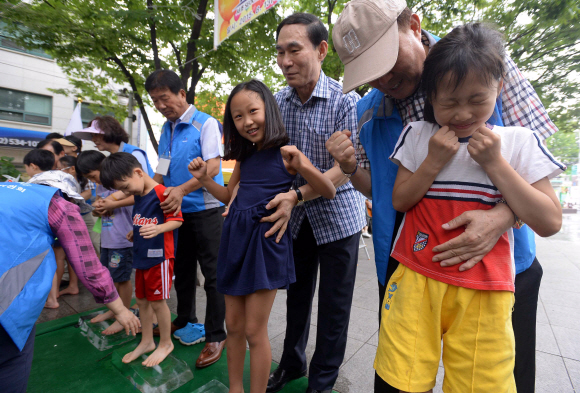 13일 서울시 서초구 뒷벌어린이공원에서 방배골 여름 축제 ’어린이 얼음 위 오래 서있기’ 대회가 열리자 참가 어린이들이 얼음 위에 올라서며 대회를 즐기고 있다.  이언탁 기자 utl@seoul.co.kr