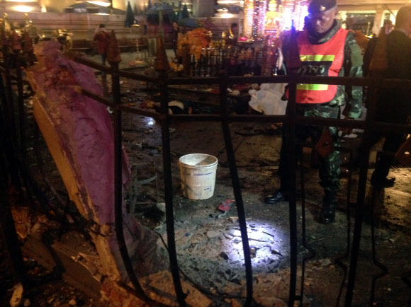 17일(현지시간) 태국 경찰이 방콕 도심의 관광 명소인 에라완 사원 근처에서 일어난 폭발로 피해를 입어 황폐해진 사원 밖을 응시하고 있다.     ⓒ AFPBBNews=News1