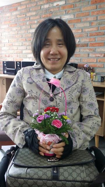 한경숙 경기 수원시 중증장애인독립생활센터장이 5월 8일 어버이날 기념행사에서 직원들이 선물한 꽃을 받고 기뻐하고 있다.  수원 중증장애인독립생활센터 제공