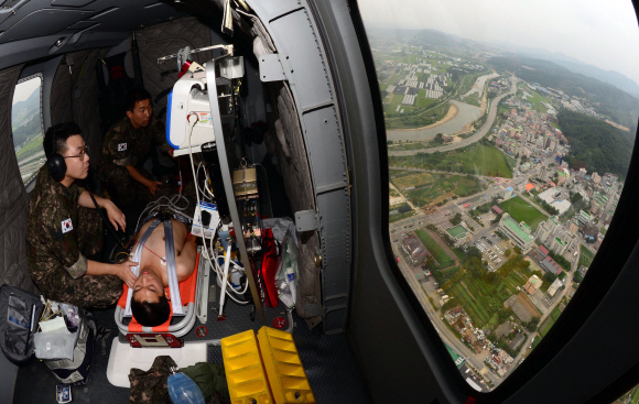 국군수도병원으로 향하는 메디온 헬기 안에서 군의관이 응급처치세트(EMS-Kit)를 이용해 환자의 상태를 살피고 있다.