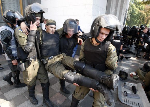 우크라이나 동부 지역에 자치권을 부여하는 데 반대하는 시위대와 경찰이 수도 키예프 의회 건물 앞에서 충돌한 가운데 경찰들이 부상을 입은 동료를 둘러메고 시위 현장을 빠져나가고 있다. 이날 우크라이나로부터 독립을 요구하는 동부 지역에 자치를 허용하는 개헌안이 의회에서 1차 심의를 통과하자 의회 앞에 모여 있던 시위대가 경찰 쪽으로 수류탄을 던져 100여명의 부상자가 발생했다. 키예프 AP 연합뉴스