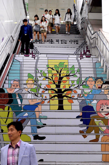 15일 서울 지하철 5호선 광화문역에 ‘독서를 권하는 계단’이 조성되자 시민들이 계단을 오르내리고 있다. 서울도시철도공사는 ‘테마계단 조성사업’ 일환으로 서울도서관, 교보문고와 업무협약을 체결하고 광화문역 계단에 독서와 관련된 다양한 이미지를 래핑해 독서를 권하는 지속적인 홍보를 이어나간다고 밝혔다.  이언탁 기자 utl@seoul.co.kr