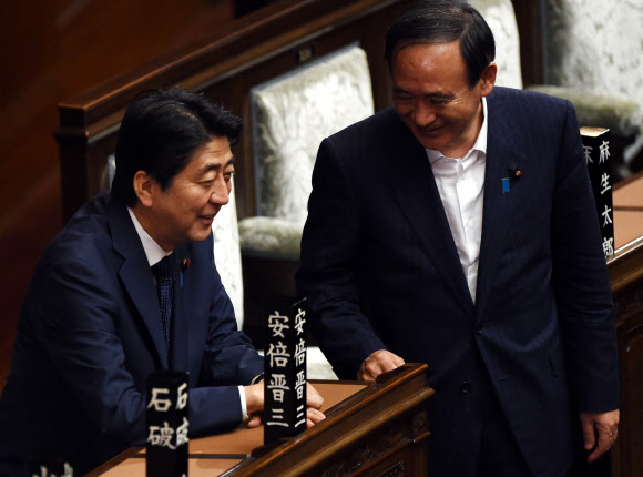 19일 새벽 일본 평화헌법을 무력화시키는 안보 관련 11개 법안의 참의원 통과가 임박하자 아베 신조(왼쪽) 일본 총리가 스가 요시히데 관방장관과 대화하던 중 웃고 있다. 일본 국회 앞에서 시민들이 법안 처리 반대 철야 시위를 벌였고 민주당 등 야당이 총리 불신임안까지 제출하며 강력 저항했지만 수적 열세를 극복하지 못했다. 도쿄 AFP 연합뉴스