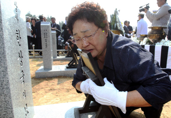 21일 대전 유성구 국립대전현충원 ‘제2연평해전 전사자 묘역’에서 한상국 중사 유족이 영정을 끌어안고 슬픔을 달래고 있다. 국가보훈처는 유족 합의에 따라 그동안 나뉘어 안장돼 있었던 6용사의 합동묘역을 새로 조성했다. 전사한지 13년 만이다. 연합뉴스