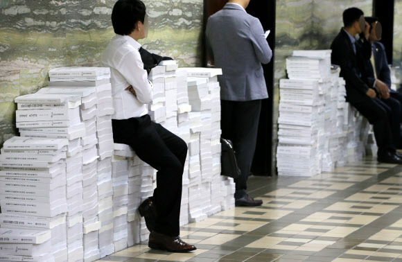 2015년도 국정감사가 계속된 21일 국회 한 상임위원회 앞 로비에서 관계자들이 가득 쌓인 국정감사 자료들 위에 앉아 잠시 쉬고 있다. 연합뉴스