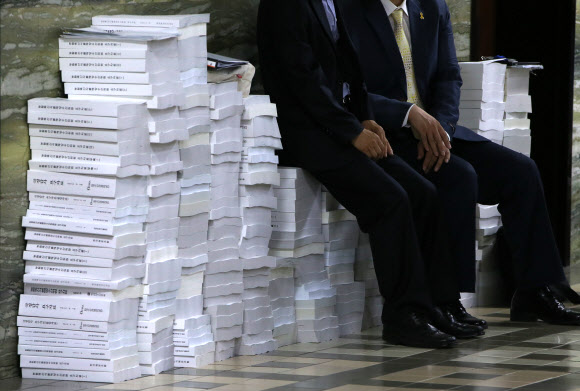 2015년도 국정감사가 계속된 21일 국회 한 상임위원회 앞 로비에서 관계자들이 가득 쌓인 국정감사 자료들 위에 앉아 잠시 쉬고 있다.   연합뉴스