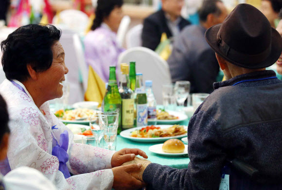 제20차 이산가족 상봉행사 2회차 둘째날인 25일 오후 금강산호텔에서 열린 공동중식에서 북측 구송옥(71) 할머니가 남측에서 온 아버지 구상연(98) 할아버지의 손을 잡고 있다.  연합뉴스