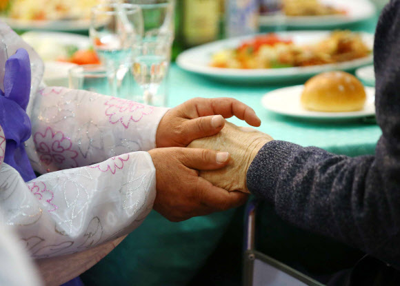 제20차 이산가족 상봉행사 2회차 둘째날인 25일 오후 금강산호텔에서 열린 공동중식에서 북측 구송옥(71) 할머니가 남측에서 온 아버지 구상연(98) 할아버지의 손을 잡고 있다.  연합뉴스