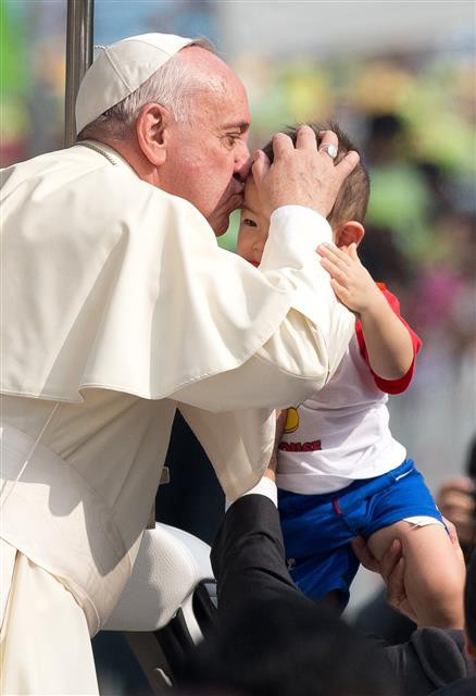 지난해 8월 프란치스코 교황이 서울 광화문광장에서 한국 초기 순교자 124위에 대한 시복식을 집전하기 앞서 카퍼레이드를 벌이던 중 한 어린이의 이마에 축복 키스를 하고 있다. 서울신문 포토라이브러리