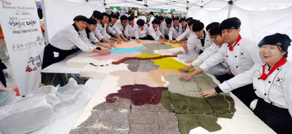 13일 서울 광화문 광장에서 열린 2015 한식의날 대축제에서 호텔조리학과 학생들이 한반도 모양의 대형떡을 손질하고 있다.  박윤슬 기자 seul@seoul.co.kr