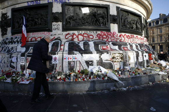 15일(현지시간) 프랑스 파리 테러 희생자들을 애도하기 위해 임시로 만들어진 추모장소에 한 시민이 애도를 표하고 있다. ⓒ AFPBBNews=News1