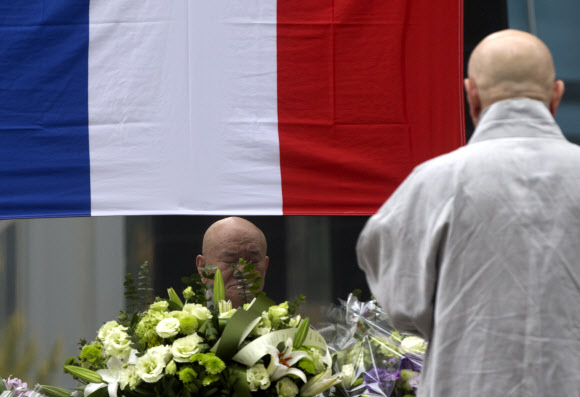 16일 오후 한 스님이 프랑스 파리 테러 희생자들을 추모하는 꽃이 놓인 서울 서대문 주한 프랑스대사관 앞에서 기도를 하고 있다.  연합뉴스