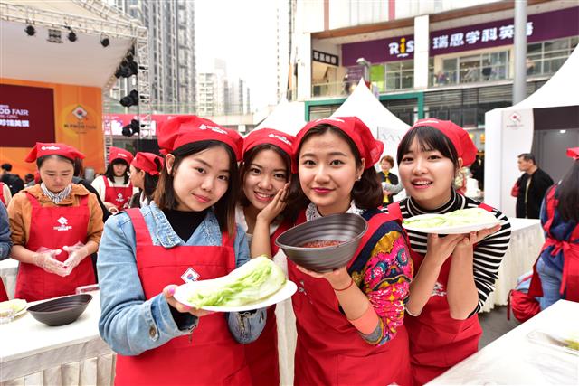 지난 7일 중국 충칭에서 열린 ‘K푸드 페어’의 김장 담그기 행사에 참가한 중국 여성들이 소금에 절인 배추와 김치속을 보여 주고 있다. 한국농수산식품유통공사 제공