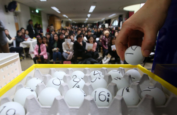 서울지역 공립유치원 신입생 추첨이 이뤄진 2일 서울 동대문구 휘경유치원에서 학부모들이 지켜보는 가운데 교사가 번호가 적힌 공을 추첨함에 넣고 있다.  연합뉴스