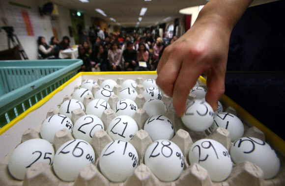 서울지역 공립유치원 신입생 추첨이 이뤄진 2일 서울 동대문구 휘경유치원에서 학부모들이 지켜보는 가운데 교사가 번호가 적힌 공을 추첨함에 넣고 있다.  연합뉴스
