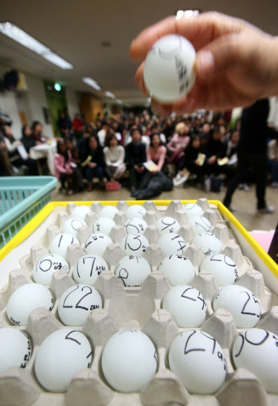 서울지역 공립유치원 신입생 추첨이 이뤄진 2일 서울 동대문구 휘경유치원에서 학부모들이 지켜보는 가운데 교사가 번호가 적힌 공을 추첨함에 넣고 있다.  연합뉴스