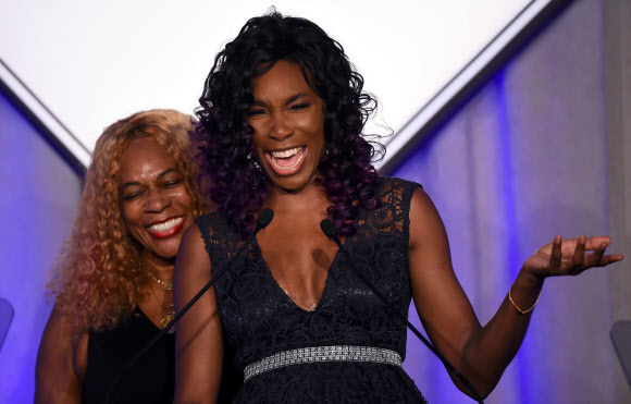 US 테니스 선수 비너스 윌리엄스가 15일(현지시간) 뉴욕에서 열린 시상식에서 동생 세레나 윌리엄스에게 올해의 스포츠 일러스레이티드 스포츠맨 트로피를 건네 주기 전에 어머니 오러신 프라이스(Oracene Price·왼쪽)을 따라 웃고 있다.  ⓒ AFPBBNews=News1