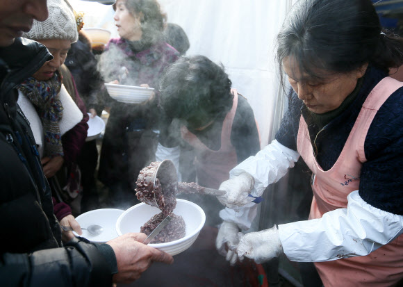 22일 서울 강남구 삼성동 봉은사에서 동지 팥죽 행사가 열려 시민들에게 팥죽을 전달하고 있다.  연합뉴스