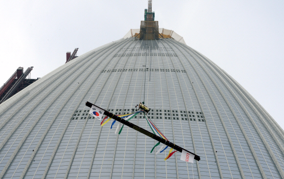 22일 오후 서울 잠실 롯데월드타워에서 열린 상량식 행사에 사용될 상량이 타워크레인에 의해 올라가고 있다.  강성남 선임기자 snk@seoul.co.kr