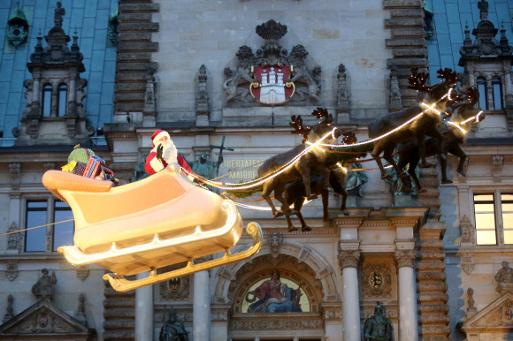 22일(현지시간) 독일 함부르크의 타운홀 앞에 산타클로스가 루돌프가 끄는 썰매를 타고 하늘을 나는  동화 같은 모습을 재현해 사람들의 시선을 끈다. ⓒ AFPBBNews=News1
