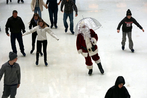 22일(현지시간) 미국 뉴욕 록펠러 센터의 스케이트장에 한 손에 투명한 비닐우산을 들고 등장한 산타클로스가 사람들 사이를 가로지르며 스케이트를 타고 있다. ⓒ AFPBBNews=News1