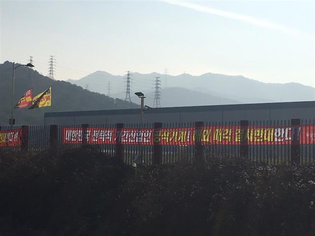 경남 창원 성산구 두산인프라코어 생산공장 외벽에 ‘해외 매각을 결사 반대한다!’는 문구가 적힌 노동조합의 현수막과 깃발이 바람에 나부끼고 있다.