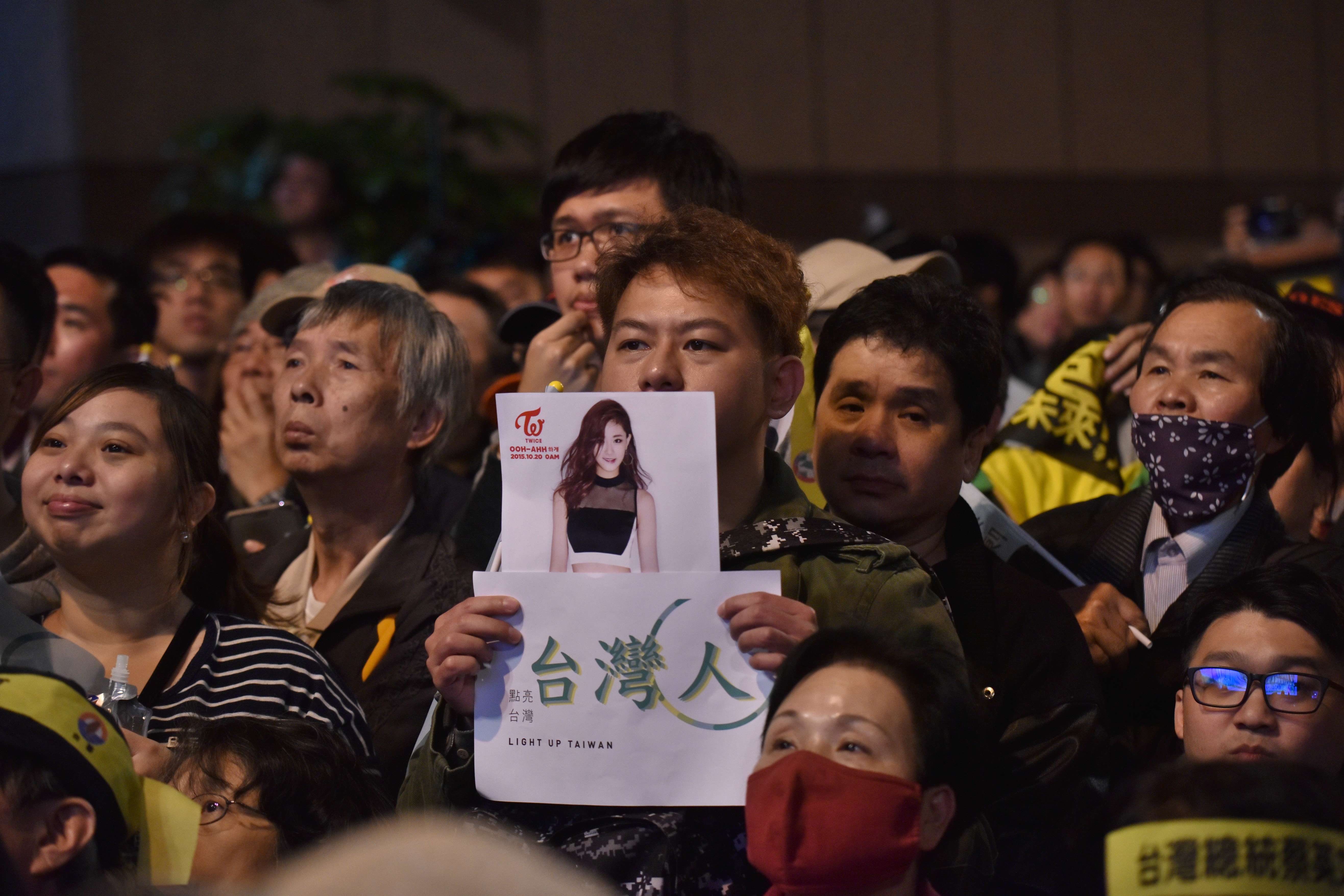 대만 민진당(DPP) 지지자가 대만 국기를 흔들어 논란이 된 쯔위의 사진을 들어보이고 있다. ⓒAFPBBNews=News1